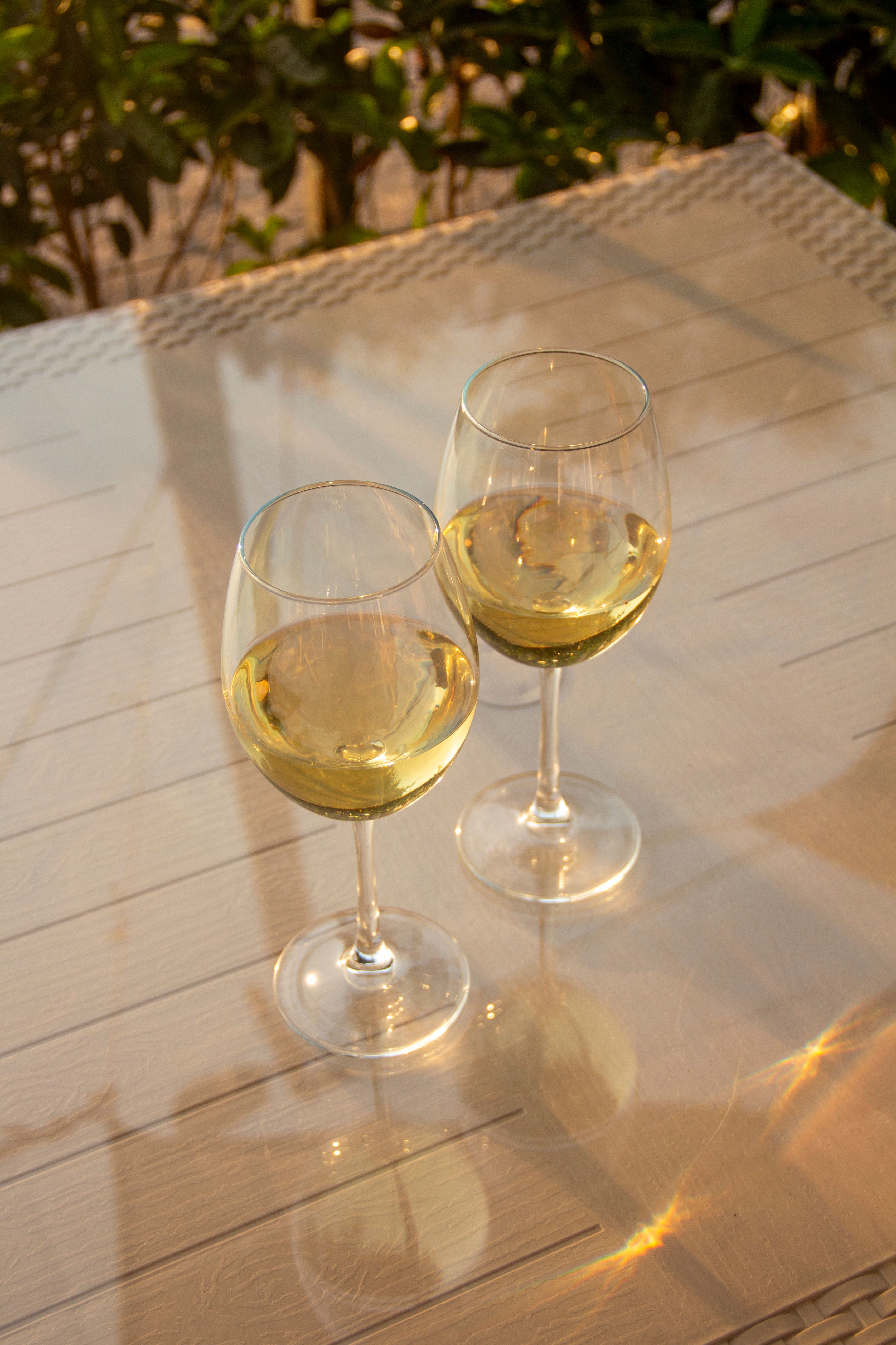 Dois copos de vinho branco sobre uma mesa ao sol